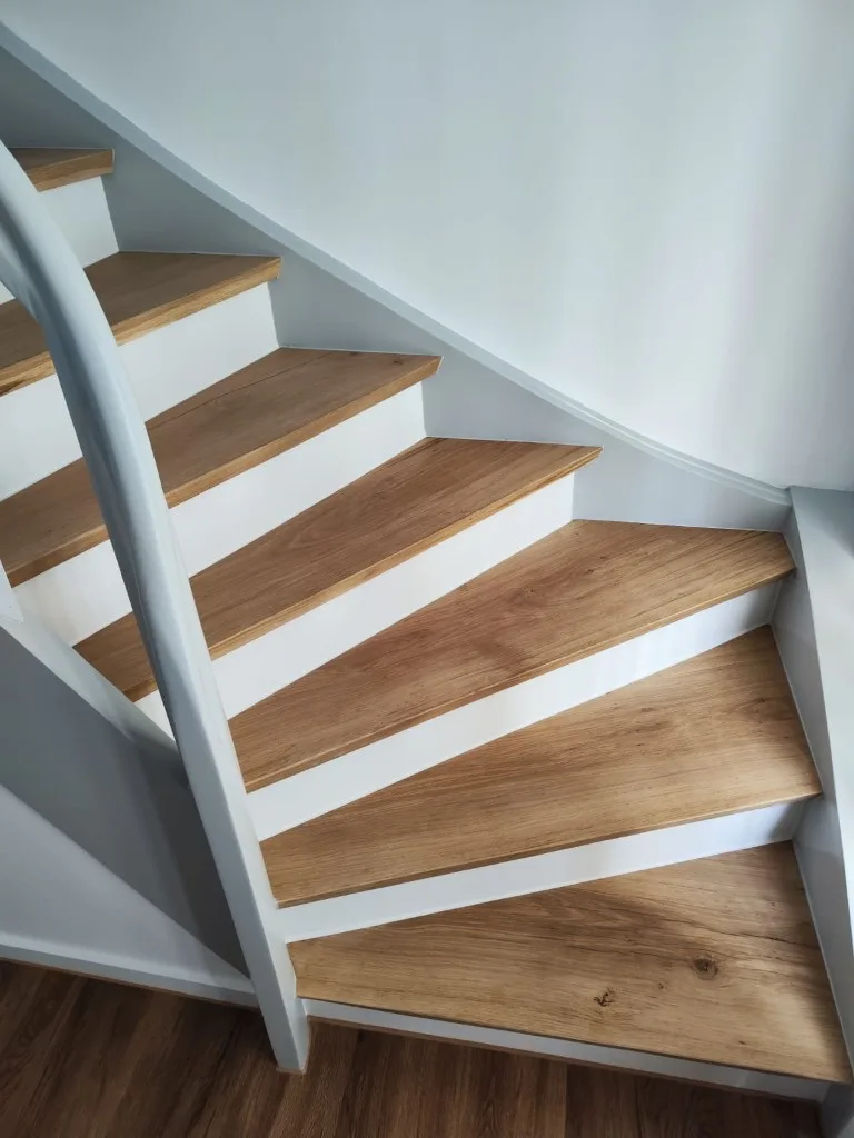 Detail der renovierten Wendeltreppe mit Holztrittstufen und weißem Handlauf